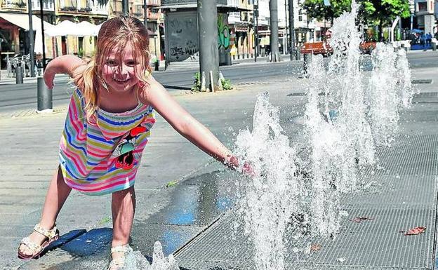 Una niña juega con los chorros de agua frente a la catedral María Inmaculada.
