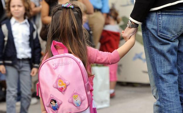 Una niña entra en el cole el primer día del curso.