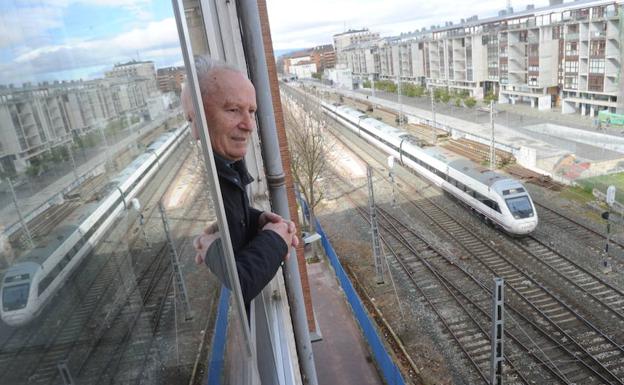 Un hombre mira desde la ventana el paso de un tren por la calle Ferrocarril de Vitoria./Igor Aizpuru
