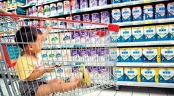 Un niño en un carro de la compra mientras su madre elige leche en China./ AFP/