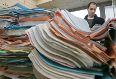 SATURADOS. Un empleado rebusca entre una montaña de expedientes en una sede judicial. / EFE/