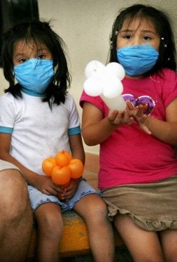 Dos niñas se protegen con mascarillas ante el temor de contraer el virus. / REUTERS/