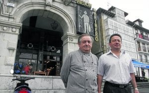 Los gerentes del mesón Marinero posan frente a la entrada al establecimiento, en el puerto pesquero de Castro. :: E. C./