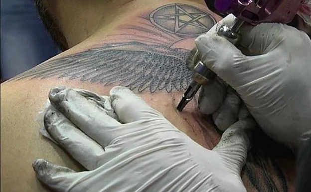 A tattoo artist performs a tattoo.  /RC