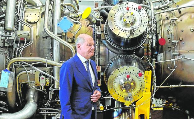 German Chancellor Olaf Scholz poses next to a turbine of the Nord Stream gas pipeline during a visit in the town of Mülheim an der Ruhr.